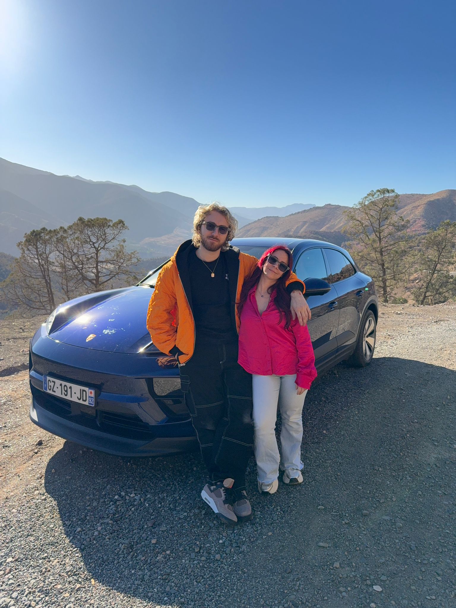 Sora et Adeline Chetail avec le Porsche Macan Électrique Sora et Adeline Chetail posant devant le Porsche Macan électrique dans le désert d’Agafay