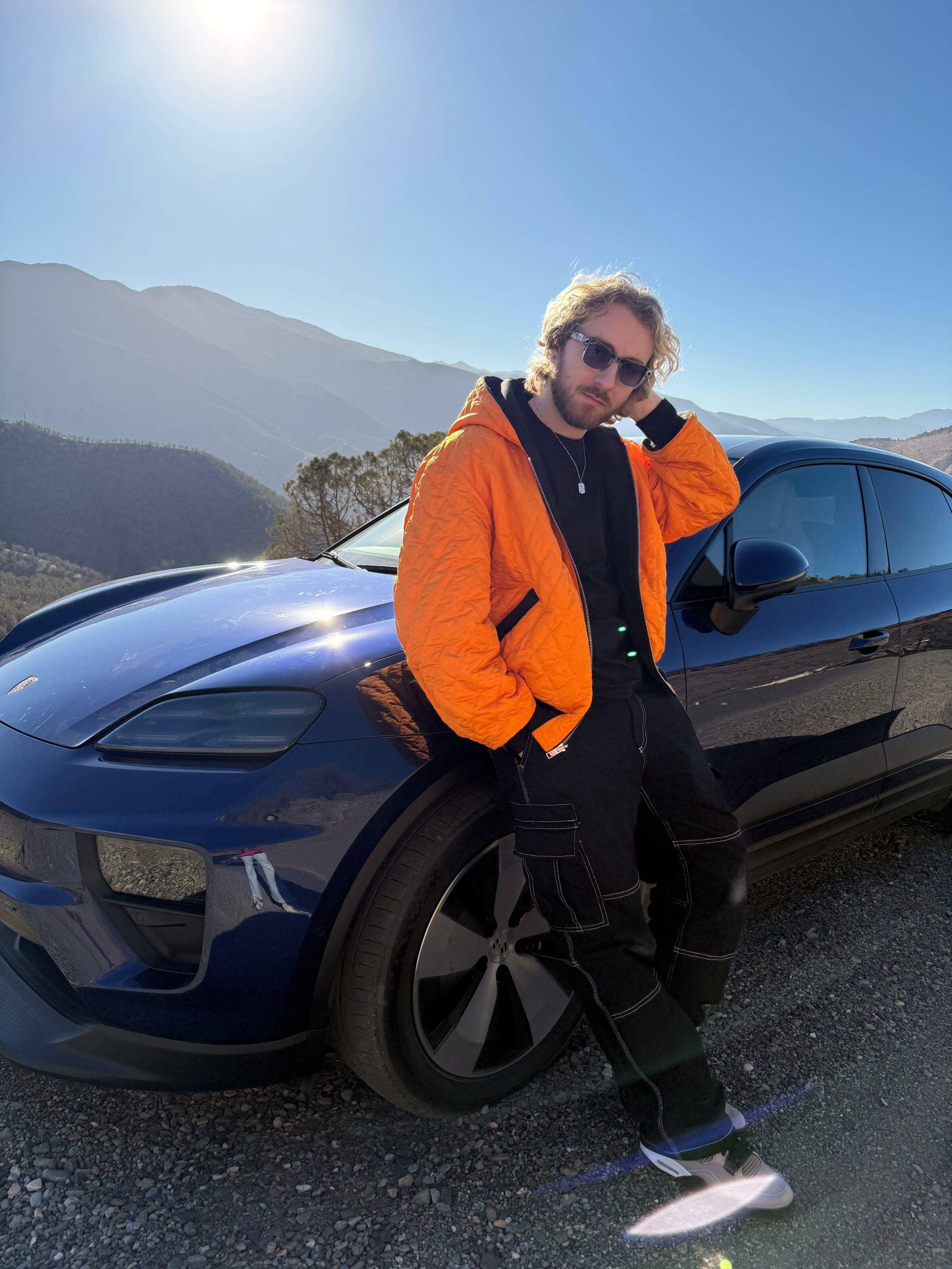 Sora et le Porsche Macan Électrique Sora posant devant le Porsche Macan électrique dans le désert d’Agafay